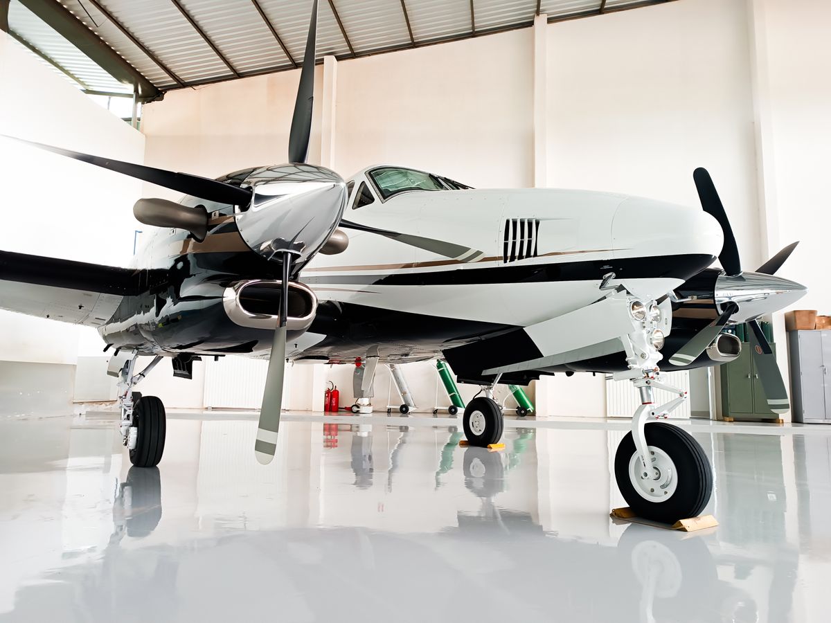 Twin-engine aircraft parked in a hangar on a light-reflective, glossy epoxy-style floor