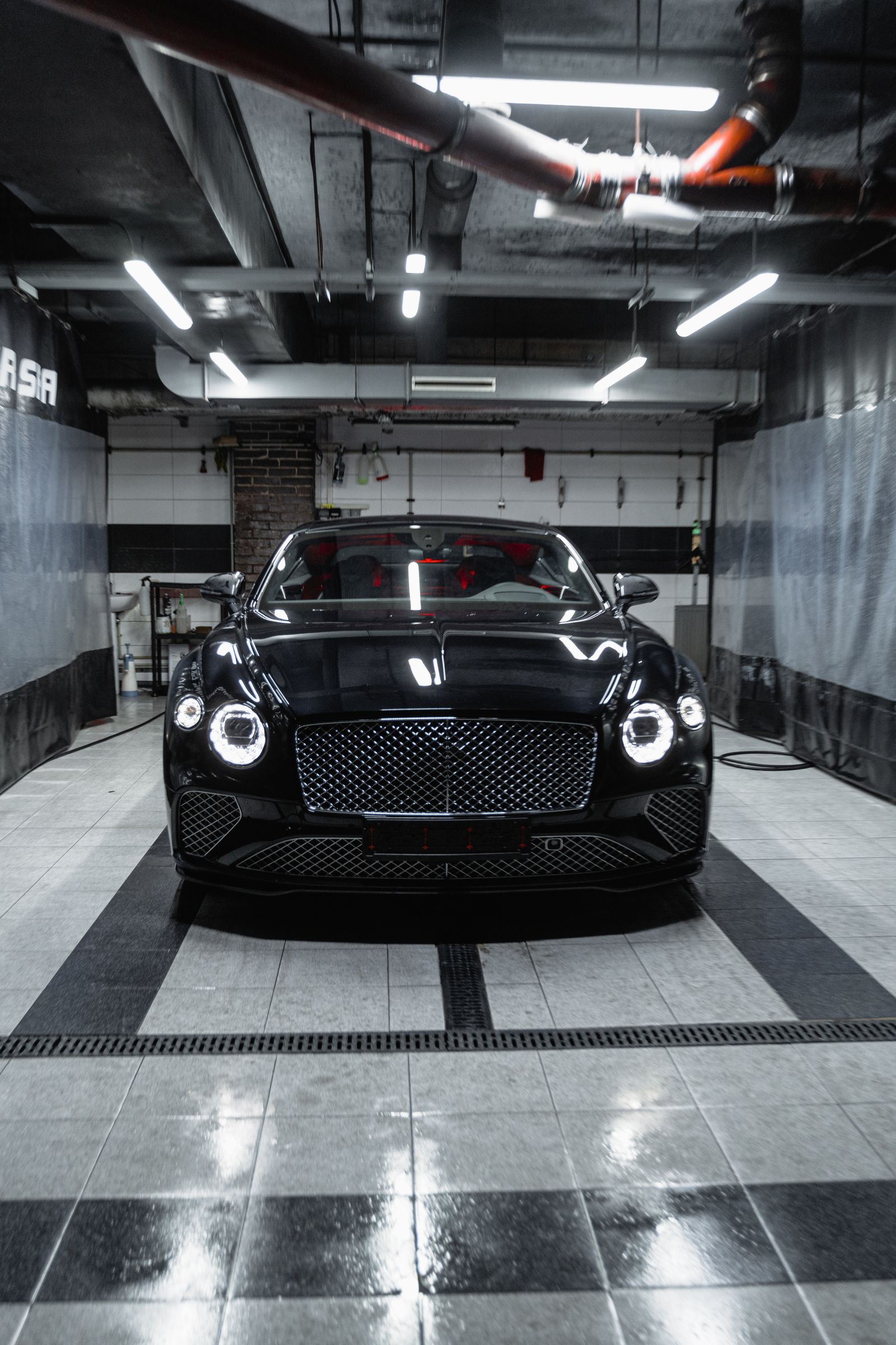 Black luxury car parked in a garage bay on a glossy, easy-clean floor