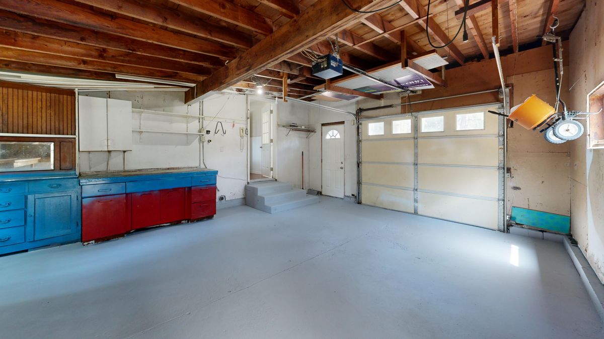 Single-car residential garage with a gray painted concrete floor and storage cabinets