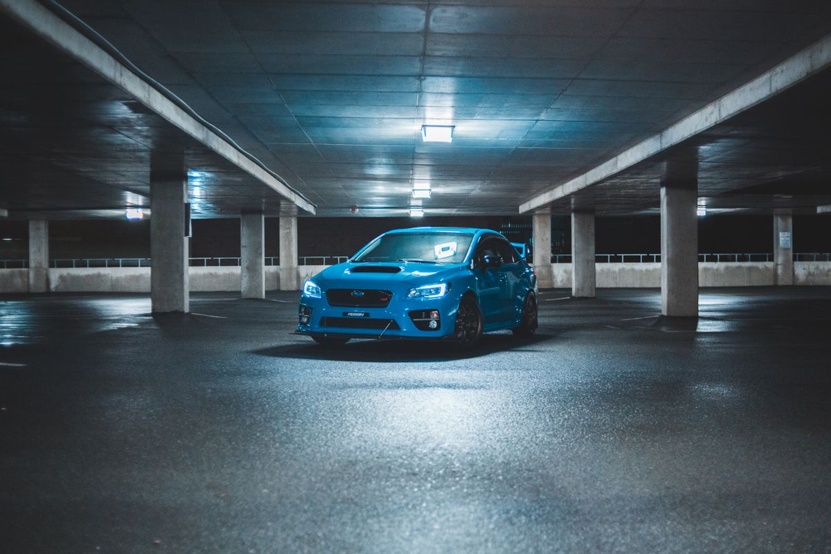 Car parked on a smooth, highly reflective sealed concrete floor in a covered parking structure